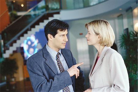 simsearch:695-05769904,k - Male and female business associates standing in lobby, man pointing at woman Foto de stock - Sin royalties Premium, Código: 695-03374460