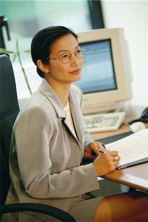 female secretary glasses - Businesswoman sitting at desk Stock Photo - Premium Royalty-Free, Code: 695-03374501