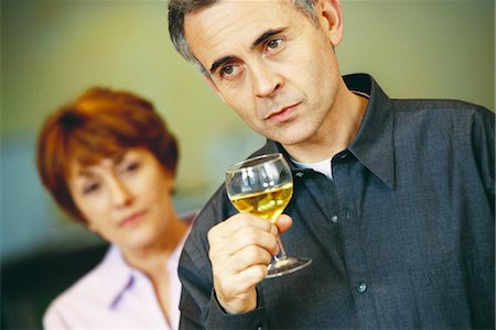 Senior man holding glass of wine, senior woman looking at him in background Stock Photo - Premium Royalty-Free, Code: 695-03374547