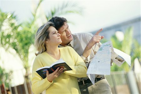 Mature couple standing outdoors with map and guidebook, man pointing Fotografie stock - Premium Royalty-Free, Codice: 695-03374549