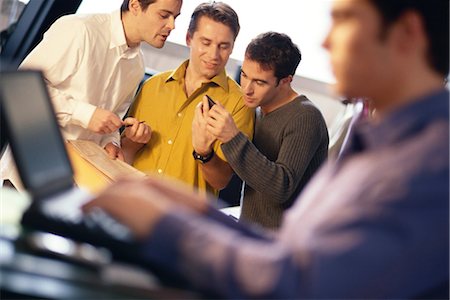 simsearch:633-01713826,k - Three young men using electronic organizer, laptop user in foreground Stock Photo - Premium Royalty-Free, Code: 695-03374559