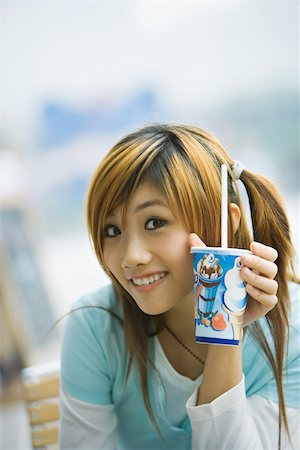 simsearch:695-03378443,k - Young woman holding up fast food drink, smiling at camera Foto de stock - Sin royalties Premium, Código: 695-03374686