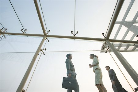 Two business executives standing in glass walkway, talking, low angle view Stock Photo - Premium Royalty-Free, Code: 695-03374761