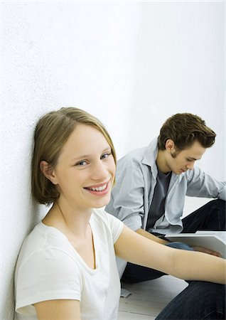 simsearch:400-03929864,k - Teenage girl and young man sitting on floor, girl smiling at camera Stock Photo - Premium Royalty-Free, Code: 695-03374771