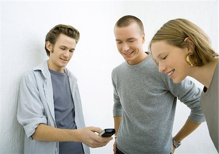 simsearch:632-01271195,k - Three young friends looking at cell phone, smiling Fotografie stock - Premium Royalty-Free, Codice: 695-03374773