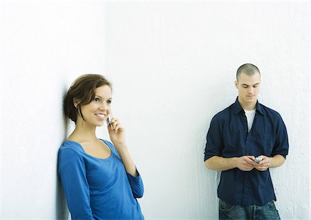 Young man and young woman using cell phones Stock Photo - Premium Royalty-Free, Code: 695-03374785