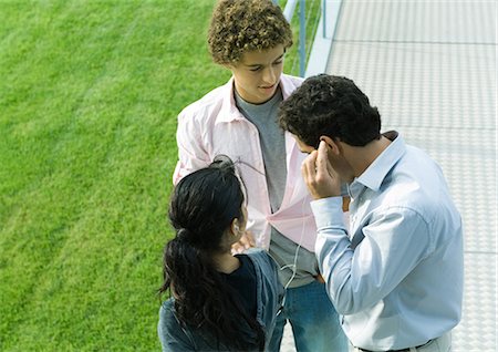 Businessman sharing earphones with teenage couple Stock Photo - Premium Royalty-Free, Code: 695-03374857