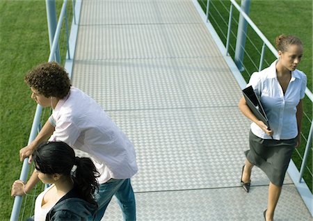 simsearch:695-05764382,k - Teenage couple leaning against rail of walkway while businesswoman walks by Stock Photo - Premium Royalty-Free, Code: 695-03374853