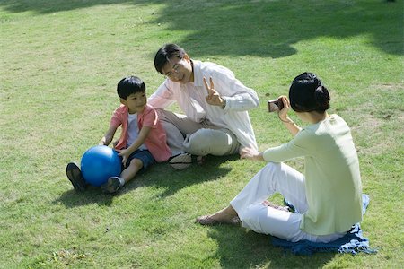 Family sitting on grass, woman taking photo of husband and son Stock Photo - Premium Royalty-Free, Code: 695-03374884