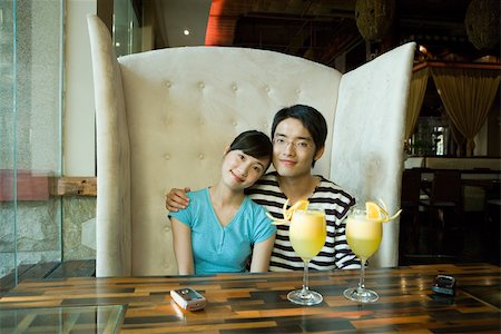 simsearch:632-01148261,k - Young couple sitting in booth, cocktails on table, smiling at camera Stock Photo - Premium Royalty-Free, Code: 695-03375073