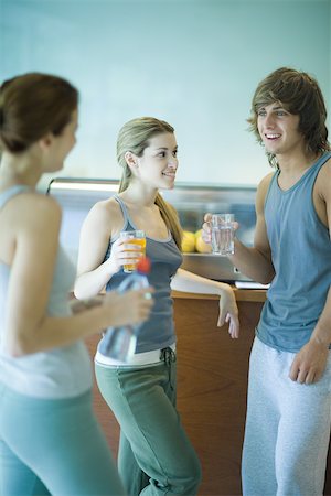 simsearch:632-07161286,k - Young adults wearing exercise clothes, standing in cafeteria, having healthy snack and chatting Stock Photo - Premium Royalty-Free, Code: 695-03375209