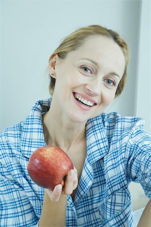 Woman wearing pajamas, holding up apple Stock Photo - Premium Royalty-Free, Code: 695-03375298