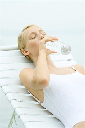 Teenage girl wearing bathing suit, sitting in lounge chair, drinking from bottle of water, eyes closed Stock Photo - Premium Royalty-Free, Code: 695-03375427