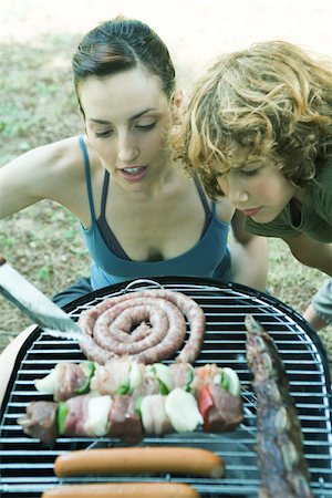 Young woman and boy bending over barbecue, looking at grilling meats Stock Photo - Premium Royalty-Free, Code: 695-03375469