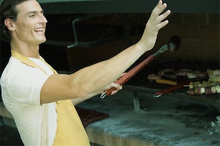 Man grilling meat on barbecue, waving out of frame Foto de stock - Sin royalties Premium, Código: 695-03375496