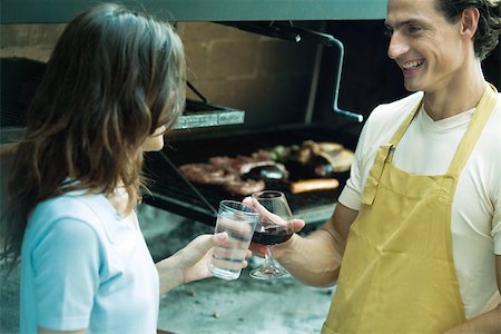 Couple clinking glasses next to barbecue Stock Photo - Premium Royalty-Free, Code: 695-03375498
