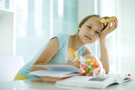 simsearch:632-03403385,k - Girl eating sweets and doing homework Stock Photo - Premium Royalty-Free, Code: 695-03375526