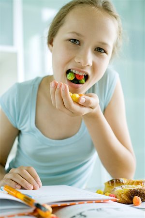 excess of junk food - Girl eating sweets and doing homework Stock Photo - Premium Royalty-Free, Code: 695-03375528