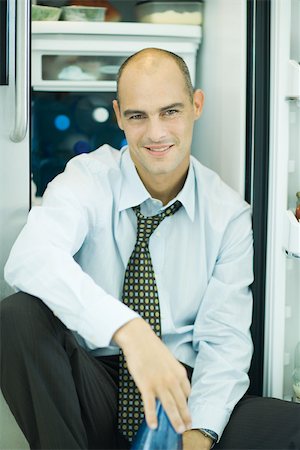 simsearch:632-05604352,k - Man sitting in front of open refrigerator, smiling at camera Stock Photo - Premium Royalty-Free, Code: 695-03375554