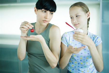 dissatisfaction - Girl holding ice cream dessert, next to woman holding cherry Stock Photo - Premium Royalty-Free, Code: 695-03375559