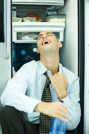 simsearch:632-05604352,k - Man sitting in front of open refrigerator, pulling on collar, head back Stock Photo - Premium Royalty-Free, Code: 695-03375553