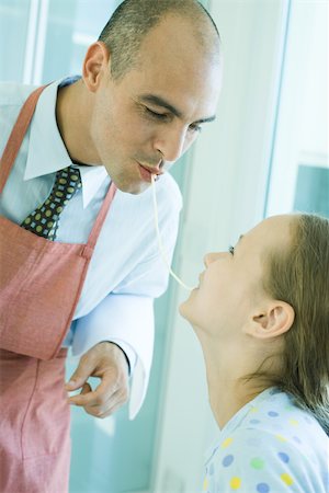 Father and daughter sharing spaghetti noodle Stock Photo - Premium Royalty-Free, Code: 695-03375567