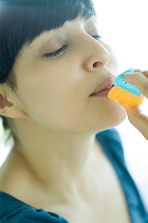 simsearch:695-05779160,k - Woman holding up piece of candy to mouth, eyes half-closed Stock Photo - Premium Royalty-Free, Code: 695-03375575