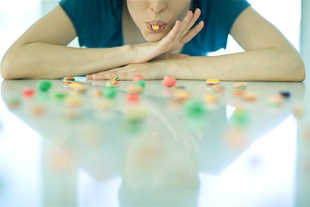 simsearch:695-03375576,k - Table spread with candy, woman resting head on arms, holding piece of candy between teeth Foto de stock - Sin royalties Premium, Código: 695-03375573