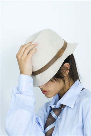Teen girl wearing shirt, tie, and hat, pulling hat down over eyes Stock Photo - Premium Royalty-Free, Code: 695-03375796