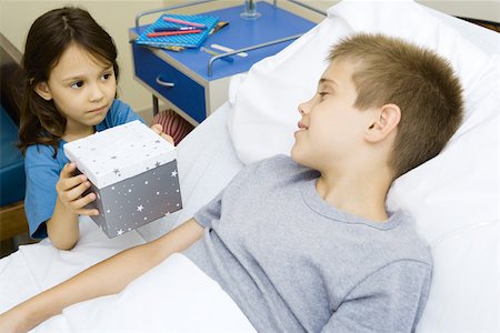 person in hospital bed overhead - Boy lying in hospital bed receiving present from girl Stock Photo - Premium Royalty-Free, Code: 695-03375858