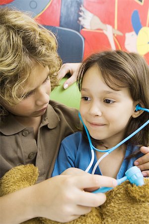 stethoscope girl and boy - Boy and girl playing doctor with teddy bear Stock Photo - Premium Royalty-Free, Code: 695-03375877
