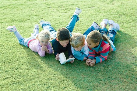 simsearch:695-03377120,k - Children lying on grass together, reading Foto de stock - Royalty Free Premium, Número: 695-03375891