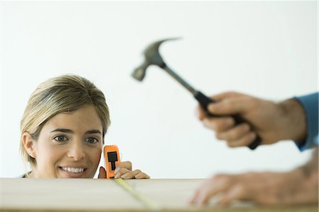 simsearch:695-03389240,k - Woman measuring board while man hammers, focus on woman in background Stock Photo - Premium Royalty-Free, Code: 695-03376050