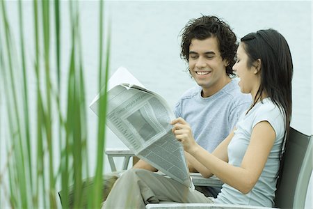 Young couple reading newspaper together by edge of lake Stock Photo - Premium Royalty-Free, Code: 695-03376071