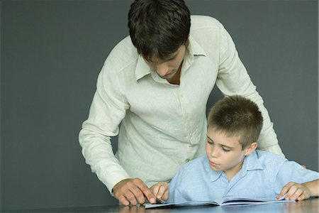 father bending over - Man helping boy with homework Stock Photo - Premium Royalty-Free, Code: 695-03376104