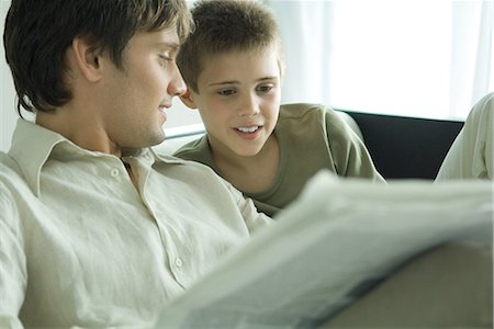 simsearch:695-03380035,k - Boy and father reading newspaper together on sofa Foto de stock - Royalty Free Premium, Número: 695-03376100