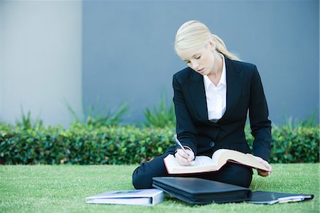 simsearch:632-01271843,k - Young businesswoman sitting on the ground outdoors, reading book, holding pen Stock Photo - Premium Royalty-Free, Code: 695-03376275