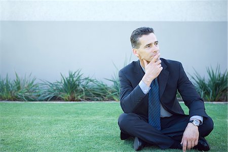 simsearch:695-03373745,k - Businessman sitting on the ground outdoors, looking away, finger on lips Foto de stock - Royalty Free Premium, Número: 695-03376270