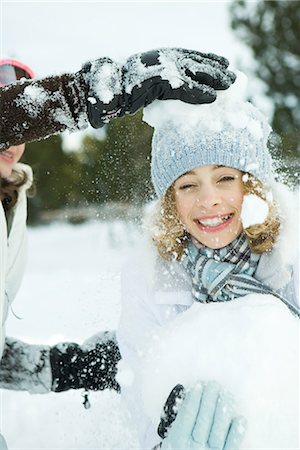 simsearch:695-03378565,k - Teenage girl being hit with snowballs, smiling at camera Foto de stock - Sin royalties Premium, Código: 695-03376302