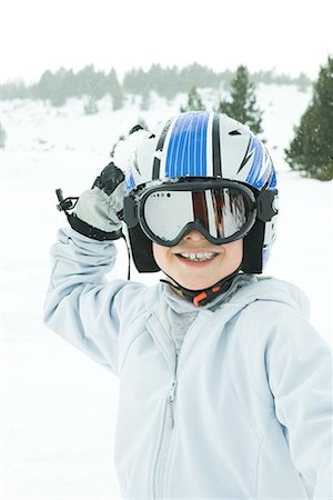 Boy holding up snowball, dressed in ski clothing, smiling at camera Stock Photo - Premium Royalty-Free, Code: 695-03376314