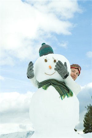 snow cone - Young man embracing snowman, looking around, portrait Stock Photo - Premium Royalty-Free, Code: 695-03376325