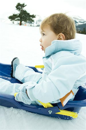 sticking out tongue in snow - Little boy sitting on sled, looking up, side view Stock Photo - Premium Royalty-Free, Code: 695-03376340