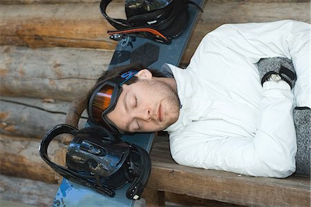 Young man lying on bench, resting head on snowboard, eyes closed Foto de stock - Sin royalties Premium, Código: 695-03376383