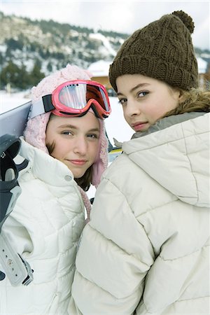 simsearch:695-03389357,k - Two teenage girls looking over shoulders at camera, one holding snowboard Stock Photo - Premium Royalty-Free, Code: 695-03376503
