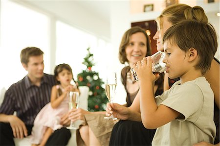 Boy drinking beverage, adults drinking champagne, Christmas tree in background Stock Photo - Premium Royalty-Free, Code: 695-03376518