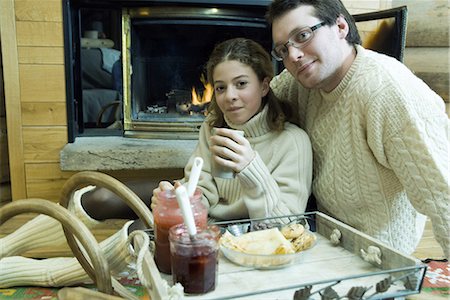 Young man and teen girl drinking hot drinks by fire place Stock Photo - Premium Royalty-Free, Code: 695-03376559