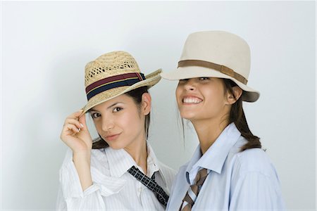 simsearch:632-01277233,k - Two young female friends wearing hats and ties, smiling at camera, portrait Fotografie stock - Premium Royalty-Free, Codice: 695-03376682