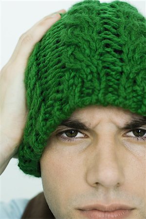 Young man wearing knit hat, looking at camera, furrowing brow Stock Photo - Premium Royalty-Free, Code: 695-03376699