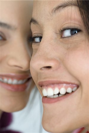 simsearch:632-01277233,k - Two young female friends smiling at camera, extreme close-up of faces, cropped Fotografie stock - Premium Royalty-Free, Codice: 695-03376792