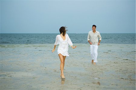 simsearch:695-05767093,k - Man and young female companion on beach, walking toward camera, man in background, full length Fotografie stock - Premium Royalty-Free, Codice: 695-03376993